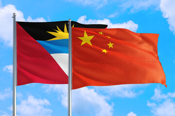 China and Antigua and Barbuda national flag waving in the windy deep blue sky. Diplomacy and international relations concept.
