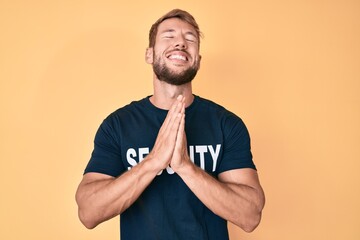 Young caucasian man wearing security t shirt begging and praying with hands together with hope...