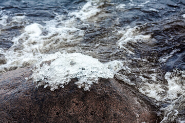 Ice on a stone in the water. Frosts, freezing water