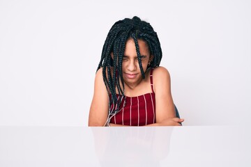 Young african american girl child with braids wearing casual clothes sitting on the table with hand on stomach because indigestion, painful illness feeling unwell. ache concept.