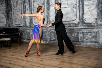 Fototapeta na wymiar beautiful couple with dance costumes dancing latin dances in the hall