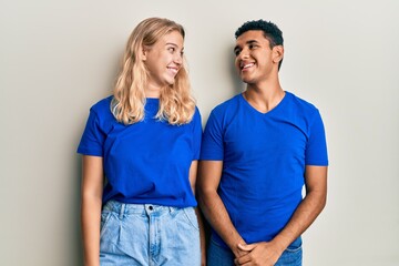 Fototapeta premium Young interracial couple wearing casual clothes smiling looking to the side and staring away thinking.