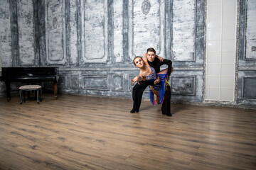 beautiful couple with dance costumes dancing latin dances in the hall