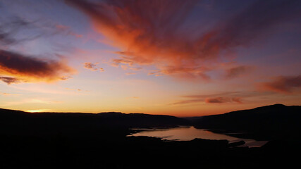 Stunning panorama view over reservoir Bin el Ouidane Dam with water reflection and beautiful colored dramatic sky with orange clouds near Beni Mellal, Morocco. 