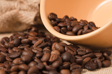 yellow coffee cup with beans and raffia cloth sacks, brown background