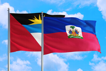 Fototapeta na wymiar Haiti and Antigua and Barbuda national flag waving in the windy deep blue sky. Diplomacy and international relations concept.