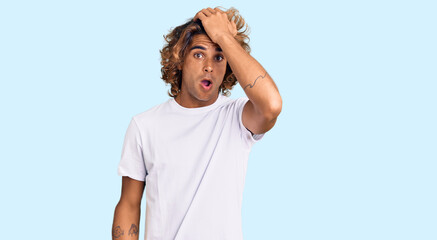 Young hispanic man wearing casual white tshirt surprised with hand on head for mistake, remember...