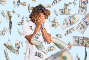 Young hispanic man wearing casual white tshirt with sad expression covering face with hands while...