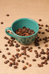 Fototapeta na wymiar green coffee cup with grains and raffia cloth background 