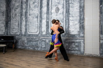 beautiful couple with dance costumes dancing latin dances in the hall