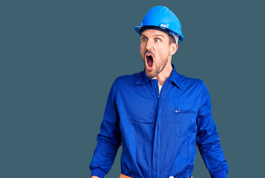 Young handsome man wearing worker uniform and hardhat doing stop gesture with hands palms, angry and frustration expression