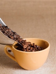 coffee, in yellow cup, and silver container, brown raffia background