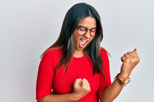 Young latin girl wearing casual clothes and glasses celebrating surprised and amazed for success with arms raised and eyes closed