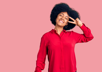 Young african american girl wearing casual clothes doing peace symbol with fingers over face, smiling cheerful showing victory