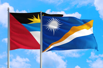 Marshall Islands and Antigua and Barbuda national flag waving in the windy deep blue sky. Diplomacy and international relations concept.