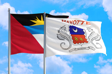 Mayotte and Antigua and Barbuda national flag waving in the windy deep blue sky. Diplomacy and international relations concept.