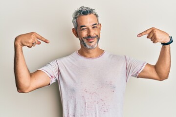 Middle age grey-haired man wearing casual clothes looking confident with smile on face, pointing...