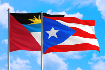 Puerto Rico and Antigua and Barbuda national flag waving in the windy deep blue sky. Diplomacy and international relations concept.