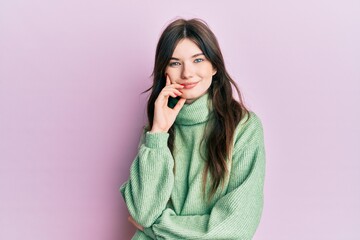 Young beautiful caucasian girl wearing wool sweater smiling looking confident at the camera with crossed arms and hand on chin. thinking positive.