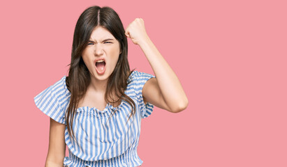 Young beautiful caucasian girl wearing casual clothes angry and mad raising fist frustrated and furious while shouting with anger. rage and aggressive concept.