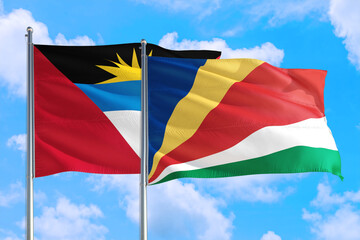Seychelles and Antigua and Barbuda national flag waving in the windy deep blue sky. Diplomacy and international relations concept.
