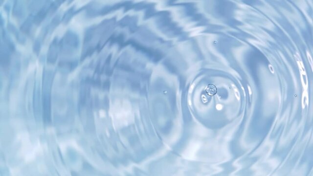 Top view slow motion of drop falling into the water surface and diverging circles on white background