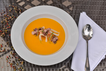 pumpkin cream soup with seafood in a white plate
