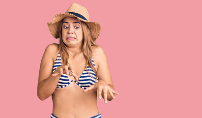 Young beautiful blonde woman wearing bikini and hat disgusted expression, displeased and fearful...
