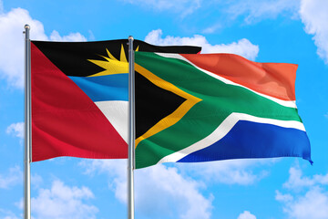 South Africa and Antigua and Barbuda national flag waving in the windy deep blue sky. Diplomacy and international relations concept.