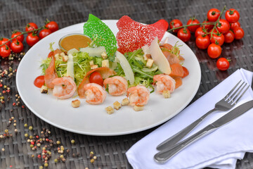 fresh salad with shrimp cherry tomatoes in a plate on a table with decor
