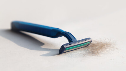 Men's blue razor and a mountain of shaved hair on a white background