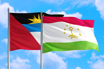 Tajikistan and Antigua and Barbuda national flag waving in the windy deep blue sky. Diplomacy and international relations concept.