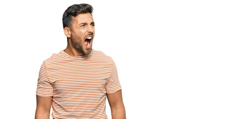 Handsome hispanic man wearing casual clothes angry and mad screaming frustrated and furious,...