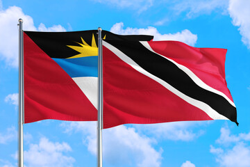 Trinidad And Tobago and Antigua and Barbuda national flag waving in the windy deep blue sky. Diplomacy and international relations concept.