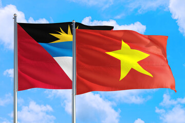 Vietnam and Antigua and Barbuda national flag waving in the windy deep blue sky. Diplomacy and international relations concept.