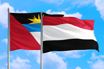 Yemen and Antigua and Barbuda national flag waving in the windy deep blue sky. Diplomacy and international relations concept.
