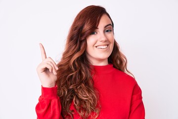 Young beautiful woman wearing casual clothes with a big smile on face, pointing with hand and finger to the side looking at the camera.