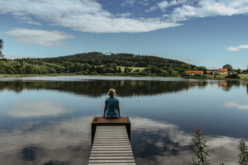 Fototapeta na wymiar Beautiful young girl meditating by lake.Harmony and meditation concept.Healthy lifestyle. Woman feeling freedom and enjoying the nature.Workout in nature.Anti-stress therapy.
