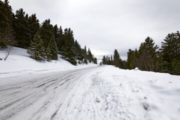 Fototapeta na wymiar Snowy mountain road streching through the hills