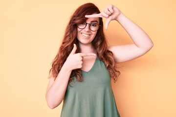 Young beautiful woman wearing casual clothes and glasses smiling making frame with hands and fingers with happy face. creativity and photography concept.