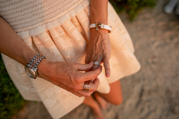 Close up on woman's hands, wearing an engagement Diamond ring, Herm√®s click H white bracelet...