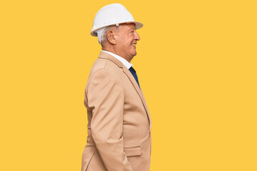 Senior caucasian man wearing architect hardhat looking to side, relax profile pose with natural face with confident smile.