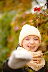 girl in a green jacket, yellow hat and scarf plays in the autumn park. cheerful joyful child playing with autumn leaves in the park. a great start to the golden autumn.