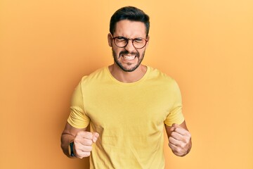 Young hispanic man wearing casual clothes and glasses excited for success with arms raised and eyes closed celebrating victory smiling. winner concept.