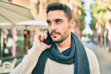 Young hispanic man with serious expression talking on the smartphone at the city.