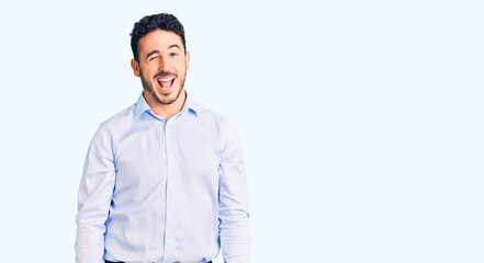 Young hispanic man wearing business clothes winking looking at the camera with sexy expression,...