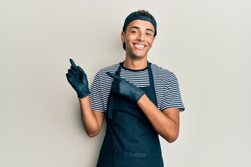 Young handsome african american man tattoo artist wearing professional uniform and gloves smiling...