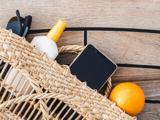 Ripe oranges, wicker basket, sunblock and sunglasses. Top view, close-up. Concept of leisure and travel