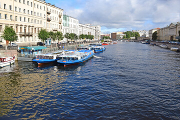 Fototapeta premium View of the Fontanka river and piers with pleasure boats from the Anichkov bridge. Russia, Saint Petersburg, September 2020