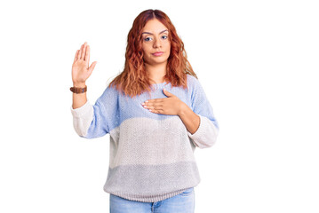 Young latin woman wearing casual clothes swearing with hand on chest and open palm, making a...